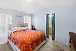 Carpeted bedroom with a textured ceiling and vaulted ceiling