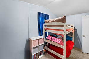 Bedroom with light colored carpet and vaulted ceiling