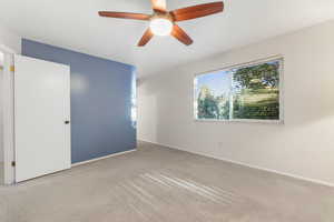 Primary ensuite bedroom with ceiling fan and carpet flooring and picture window