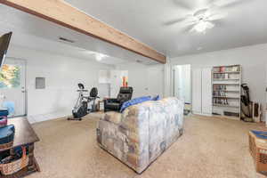 Living room with beam ceiling, a textured ceiling, and ceiling fan
