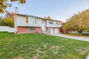 Bi-level home featuring brick siding, a chimney, driveway, and a garage