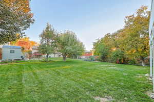 Fenced backyard featuring a storage unit