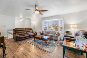 Living room featuring a textured ceiling, ceiling fan, and hardwood / wood-style flooring