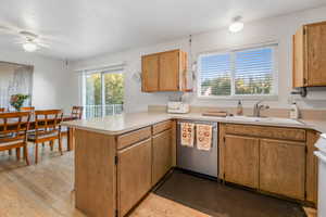 Kitchen with a peninsula, healthy amount of natural light, dishwasher, light countertops, and a textured ceiling