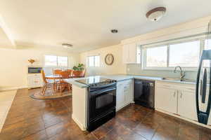 Kitchen featuring white cabinetry, black appliances, a peninsula, light countertops, and tile flooring