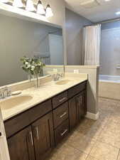Bathroom featuring a textured ceiling, double vanity, and light tile patterned floors