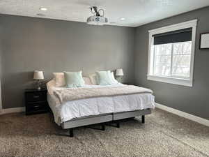 Carpeted bedroom featuring a textured ceiling and recessed lighting