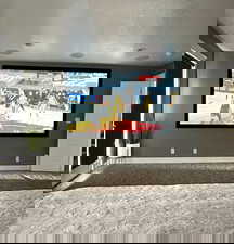 Carpeted cinema featuring a textured ceiling and golf simulator