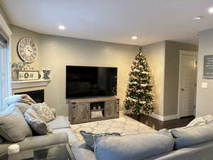 Living area with wood finished floors, recessed lighting, a fireplace, and a textured ceiling
