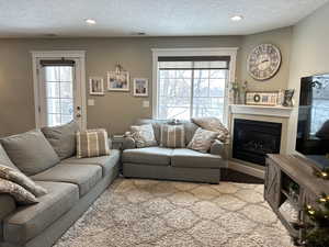 Living area with a textured ceiling, a glass covered fireplace, and recessed lighting