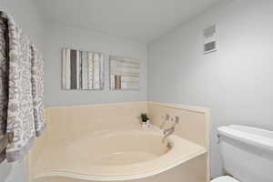 Bathroom with a garden tub and toilet