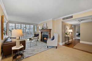 Carpeted living room featuring crown molding, a fireplace, and wood finished floors