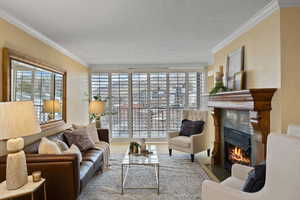 Living room featuring crown molding, plenty of natural light, a fireplace, a textured ceiling, and wood finished floors