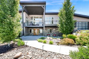 Back of property featuring stone siding and a balcony