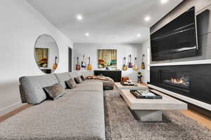 Living room featuring light wood finished floors, a glass covered fireplace, and recessed lighting