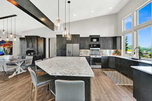 Kitchen featuring stainless steel appliances, a breakfast bar, beam ceiling, backsplash, and pendant lighting