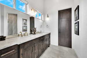 Bathroom featuring double vanity, light tile patterned flooring, and an enclosed shower