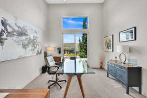 Carpeted home office with a high ceiling and baseboards