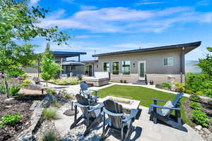 Back of property featuring a hot tub, a patio, a fire pit, a yard, and entry steps