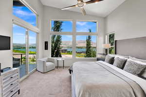 Bedroom featuring a water and mountain view, light carpet, access to outside, a ceiling fan, and high vaulted ceiling
