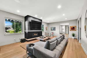 Living room with light wood-style flooring, recessed lighting, and a fireplace