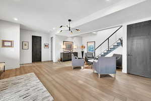 Living room with a chandelier, recessed lighting, light wood finished floors, and stairway