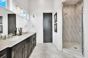 Bathroom with double vanity, a stall shower, and light tile patterned floors