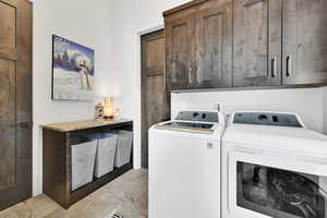Washroom featuring independent washer and dryer, cabinet space, and light marble finish floors