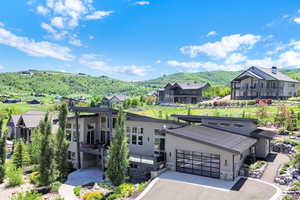 View of front of property with concrete driveway, stone siding, a balcony, a mountain view, and a garage