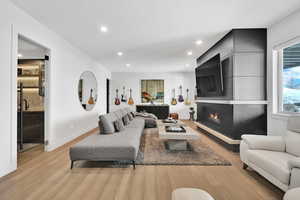 Living room with light wood-style flooring, recessed lighting, and a large fireplace
