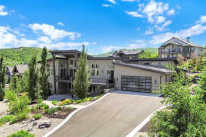 Contemporary home featuring stone siding, driveway, a balcony, and an attached garage