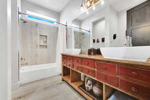 Bathroom with double vanity, shower / bath combo, and light wood finished floors