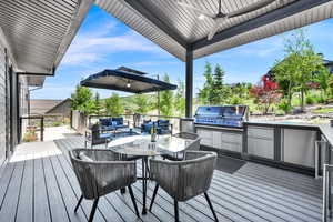 Wooden deck featuring outdoor dining space, area for grilling, and ceiling fan