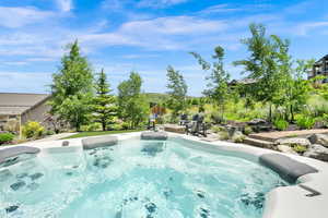 View of swimming pool with a hot tub, a fire pit, and a patio