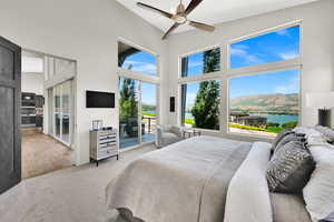 Carpeted bedroom with access to outside, a high ceiling, and a ceiling fan