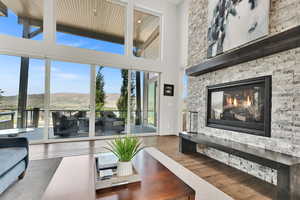 Living area featuring a mountain view, dark wood-style flooring, a stone fireplace, and a high ceiling