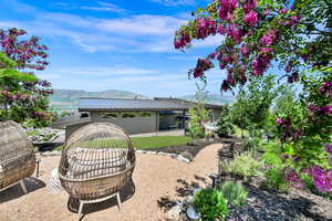 Back of house with a mountain view, a metal roof, a fire pit, a patio area, and a garage