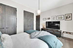 Bedroom with multiple closets and wood finished floors