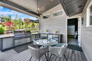 Wooden terrace featuring outdoor dining space and exterior kitchen