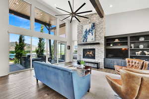 Living area with hardwood / wood-style flooring, a fireplace, beamed ceiling, a mountain view, and a towering ceiling