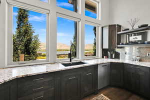 Kitchen with a mountain view, light stone countertops, decorative backsplash, dark wood-type flooring, and open shelves
