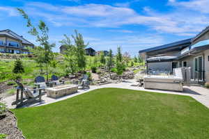 View of grassy yard featuring a patio, a hot tub, and a fire pit