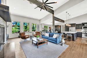 Living area with a glass covered fireplace, light wood-style flooring, a chandelier, recessed lighting, and a ceiling fan