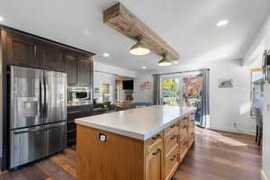 Kitchen with stainless steel appliances, dark wood-style flooring, beamed ceiling, recessed lighting, and a kitchen island