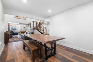Dining area with dark wood-style flooring, stairway, and recessed lighting