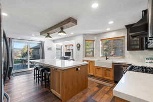 Kitchen featuring a kitchen island, a textured ceiling, backsplash, dark wood-style flooring, and brown cabinetry
