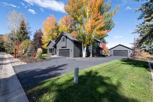 View of front of home with a detached garage and a front yard