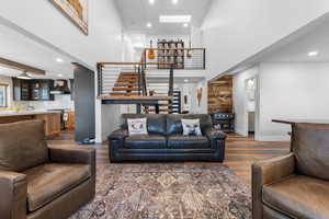 Living area featuring a high ceiling, recessed lighting, dark wood-type flooring, and stairway