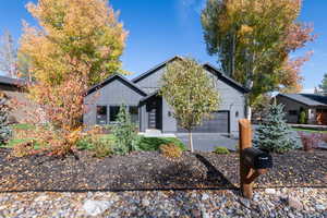 View of front facade with board and batten siding, driveway, and a garage