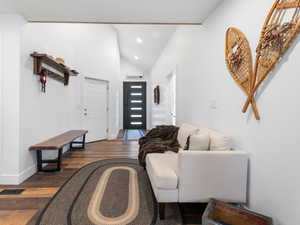 Foyer entrance with dark wood-style flooring, high vaulted ceiling, and recessed lighting